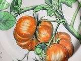 two orange tomatoes on a plate with green leaves