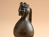 une vieille figurine en bronze représentant un oiseau avec une fleur sur la tête