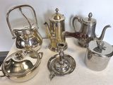 de nombreuses théières et cafetières en argent posées sur une table