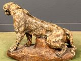 statue of a lion on a rock on a green surface