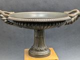 a metal bowl with two snakes on top of it