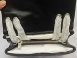 someone is holding a black purse with white gloves on it