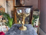 a gold wine glass sitting on top of a wooden table