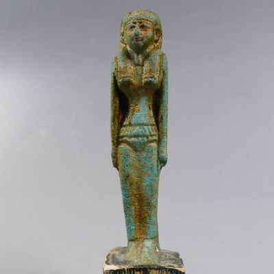 une statue égyptienne représentant une femme tenant un oiseau sur un socle