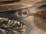 a silver vase with a leaf on it on a table