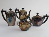un service à thé composé de quatre pièces en verre d'art, posé sur un support blanc