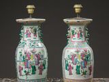 pair of chinese vases with figures on them sitting on a table