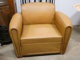 a tan leather chair sitting in the corner of a room