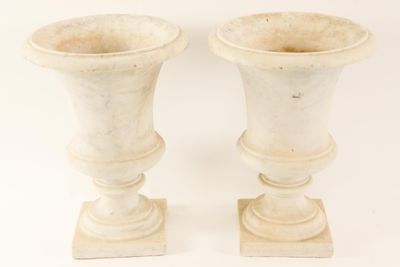 two white vases sitting next to each other on a white surface