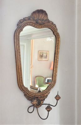 a mirror hanging on the wall next to a wall sconce