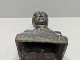 bronze statue of a man sitting in a box on a white surface
