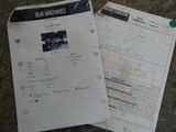 two papers on a table with a picture of a car in the background