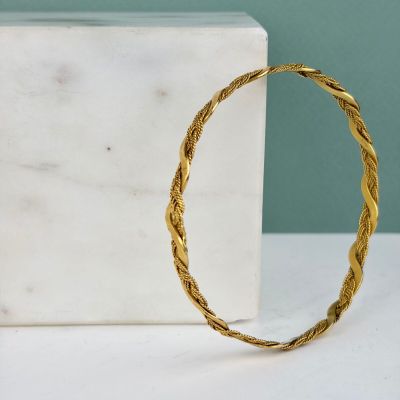 une image représentant un bracelet en or posé sur un bloc de marbre