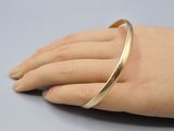 the hand is holding a gold bracelet on it ' s arm