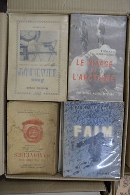 Plusieurs livres sont empilés dans une boîte en carton posée sur une table
