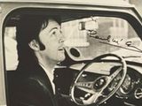 photographie en noir et blanc d'un homme assis dans une voiture, la main sur le volant