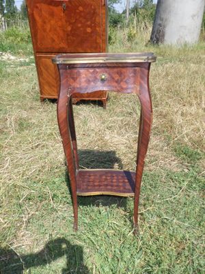 une petite table avec un tiroir, posée dans l'herbe