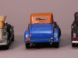 four toy cars are lined up in a row on a gray surface