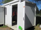 un petit bâtiment blanc devant lequel se trouve une chaise verte