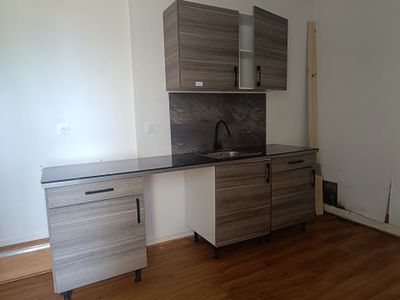 a kitchen with a sink, cabinets, and a refrigerator in it