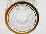 a clear glass bottle with a gold rim on a white surface