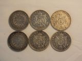six different british coins sitting on top of a white surface
