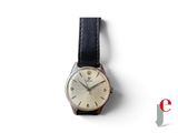 une image représentant une montre posée sur une surface blanche, avec un logo en arrière-plan