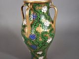 un vase vert orné de fleurs bleues, posé sur une table