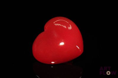un objet rouge en forme de cœur posé sur une surface noire