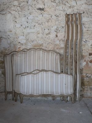 a bed that is next to a wall with a curtain