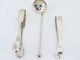 three silver spoons and a spoon rest on a white surface
