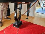 a man standing next to a black piano on a red rug