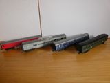Plusieurs petits trains sont alignés sur une table près d'un mur.
