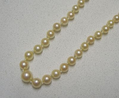 un gros plan d'un collier de perles blanches posé sur une table