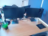 two computer monitors sitting on top of a wooden desk