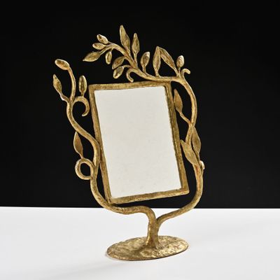 gold leafy mirror on a stand on a white surface