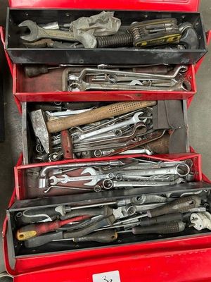 de nombreux outils dans une boîte à outils rouge posée par terre