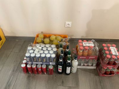 Des bouteilles et des canettes de soda sont posées par terre près d'un mur.