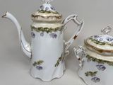 two teapots with flowers on them sitting next to each other