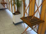 une chaise pliante en bois posée dans un couloir, à côté d'une plante en pot