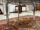 une table en verre avec un piètement en métal, posée sur un tapis