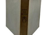 an old book with a gold cover sitting on top of a white table