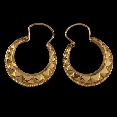 a pair of gold hoop earrings on a black background