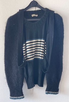 a sweater hanging on a hanger on a white wall