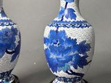 pair of blue and white vases sitting on top of a wooden stand