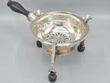 an antique silver plate with a black handle and a wooden handle