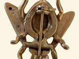 a gold brooch with a bird and a fish on it