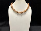 a white mannequin with a wooden bead necklace on it