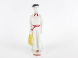 figurine représentant une femme en robe blanche avec un sac jaune