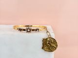 un bracelet en or orné d'une breloque en forme de pièce de monnaie posée sur un bloc de marbre